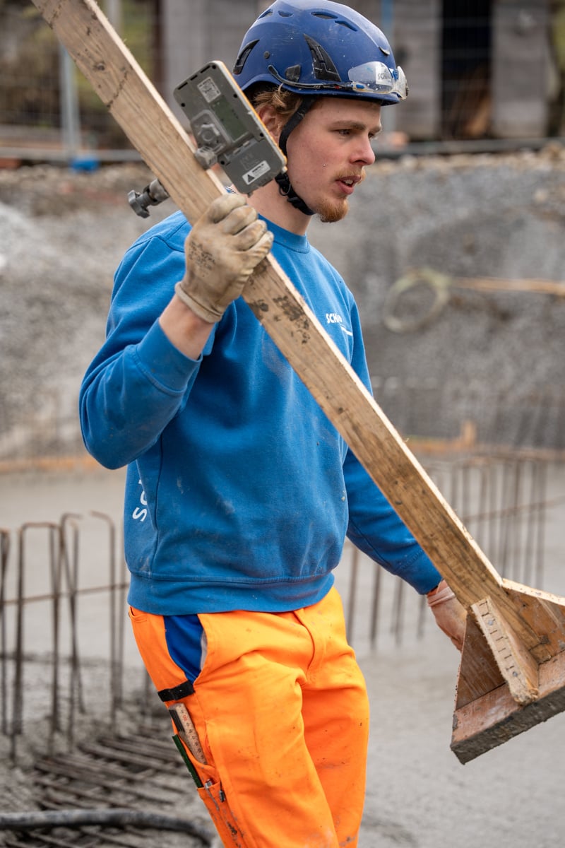 Lehrender Maurer läuft auf den Armierungseisen einer Baustelle