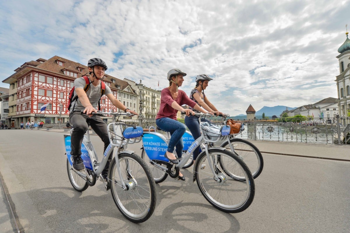 3 Personen fahren ein Next bike in der Stadt Luzern.
