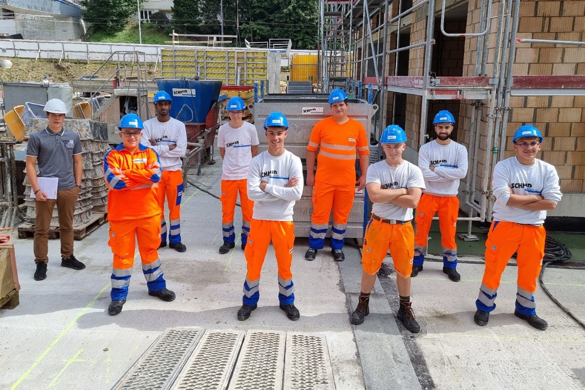 Gruppenfoto Lernende in Arbeitskleidung auf Baustelle.
