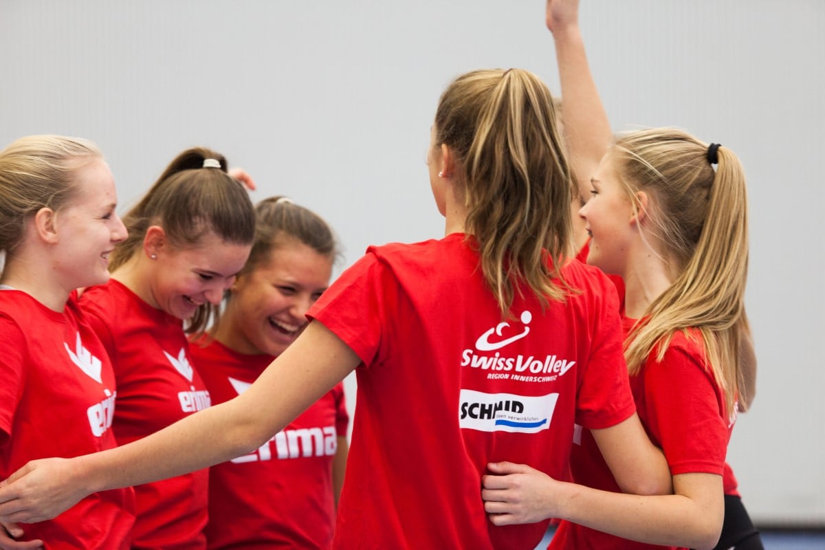 Volleyball Spielerinnen in roten T-Shirts umarmen sich zum Sieg.