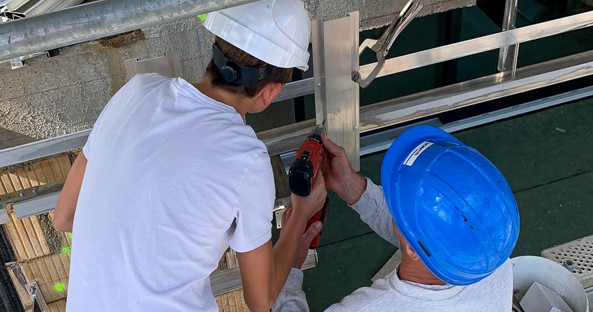 Bauarbeiter und Schüler zusammen beim Fassadenbau.