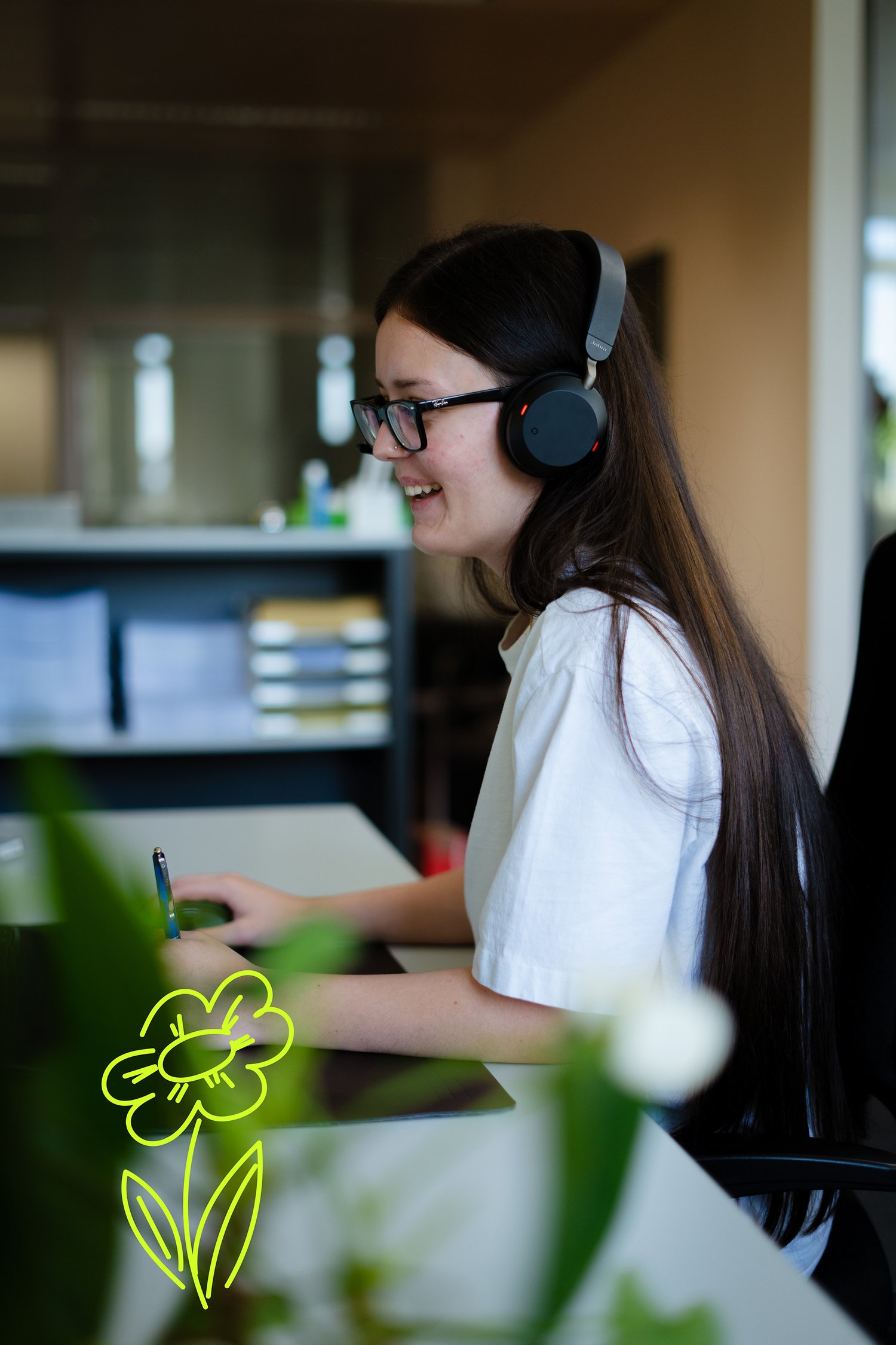 Schmid KV Lernende sitzt lächelnd am Arbeitsplatz und telefoniert mit Headset.