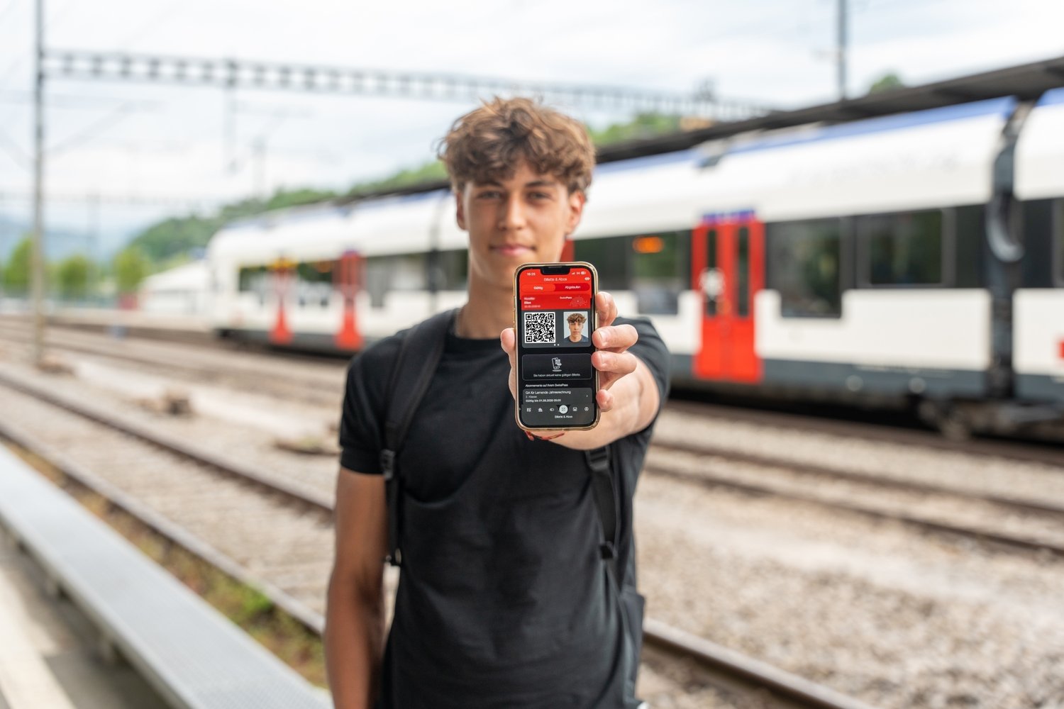 Lernender Maurer streckt Handy in die Kamera und zeigt sein GA Abo der SBB
