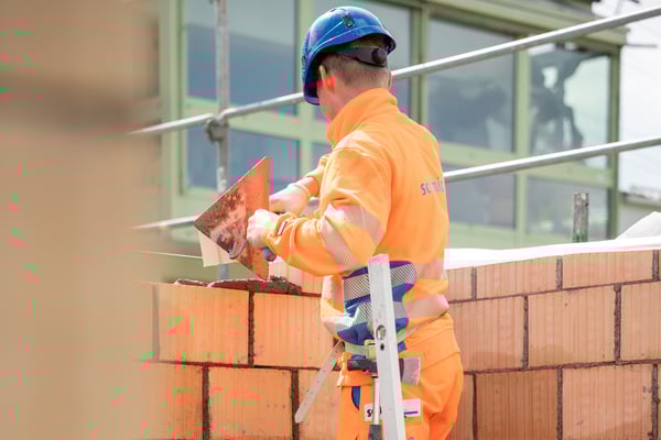 Maurerlernender beim errichten einer Mauer