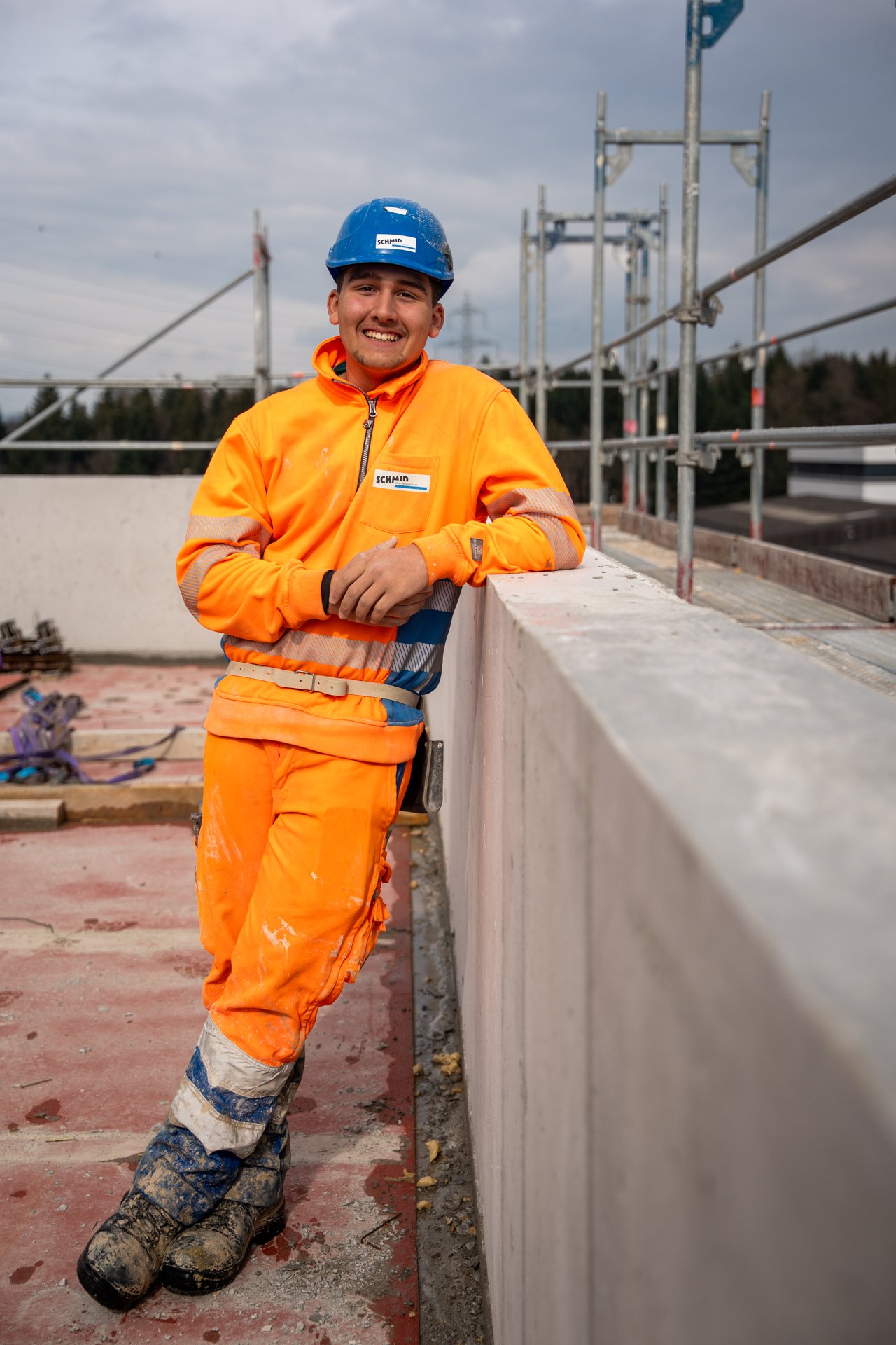 Lernender Maurer auf der Baustelle in Rothenburg lächelt in die Kamera.