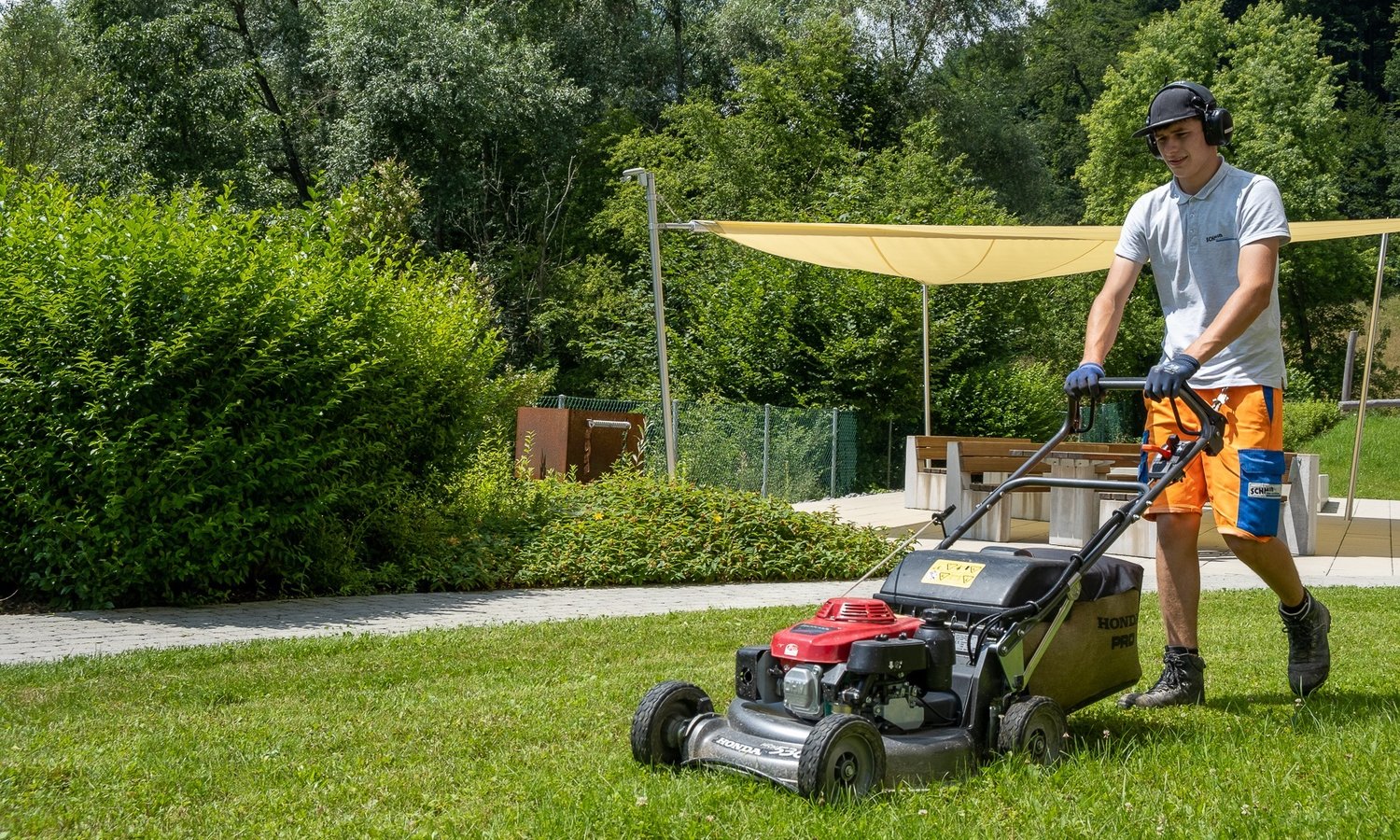 Gartenbaumitarbeiter beim Rasenmähen