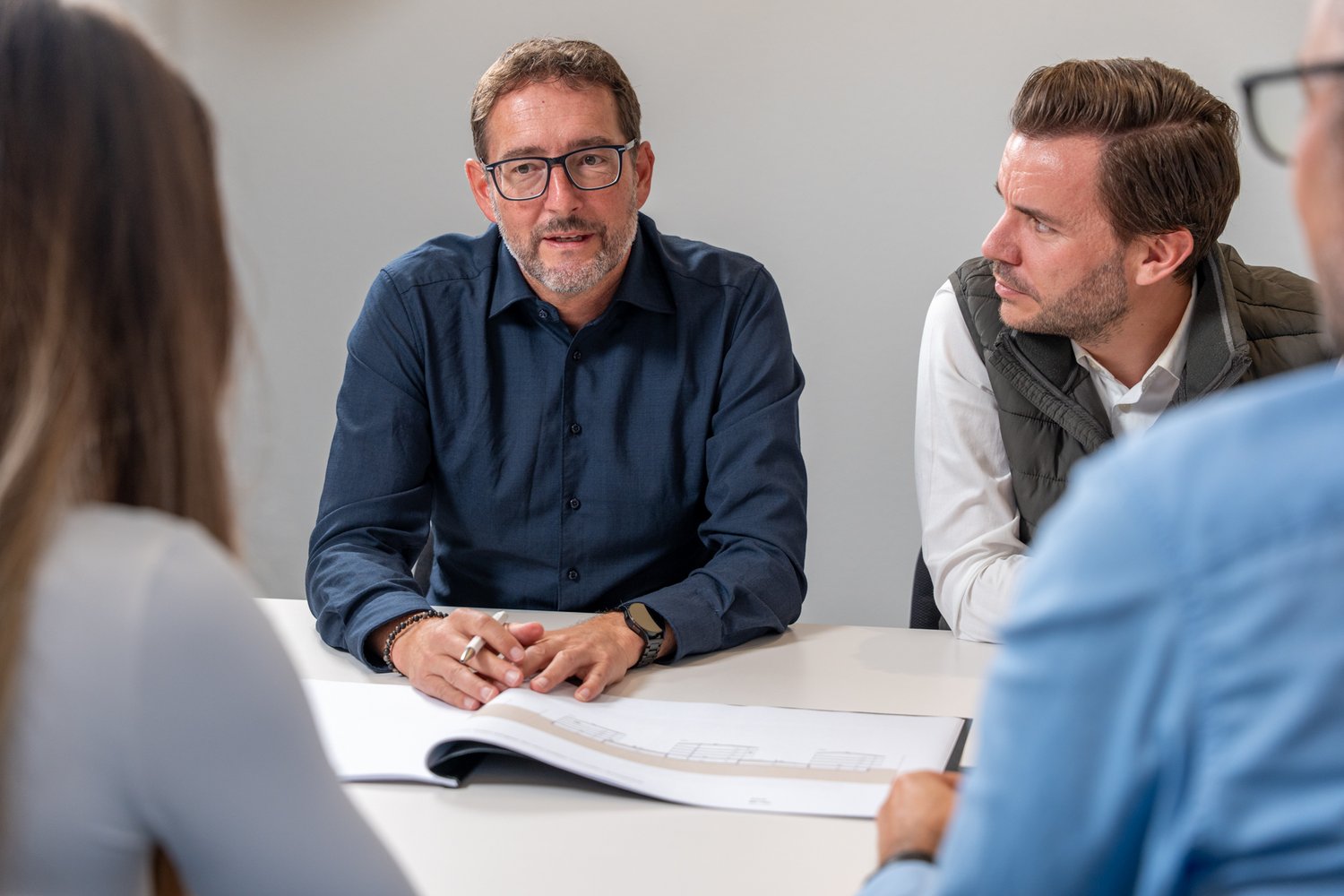 vier Personen im Gespräche an einer Sitzung