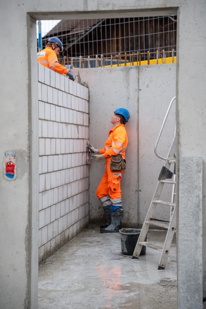 Zwei Maurer Lernende, die eine Mauer erstellen