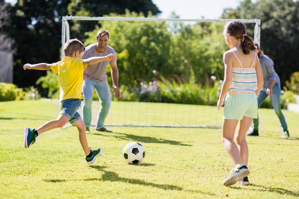 Kinder die Fussballspielen auf einer Wiese.
