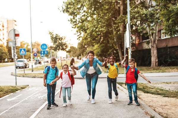 Eine Erzieherin mit vier Kindern auf dem Gehweg.